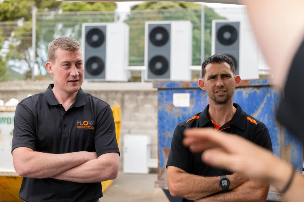 Two Flow Heating installers standing in front of air to water heat pump units