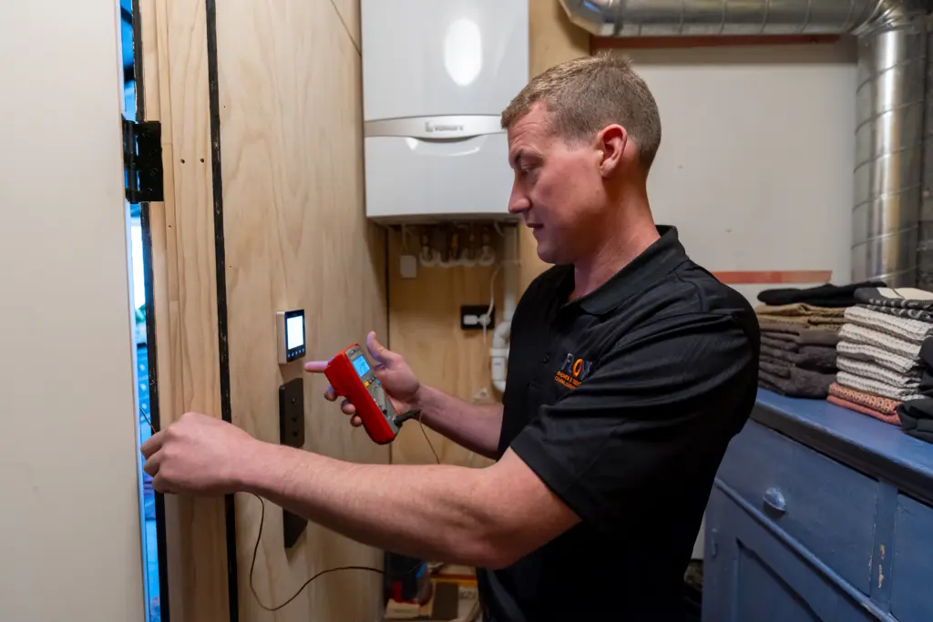 Flow Heating technician fitting a heating control unit in a kitchen