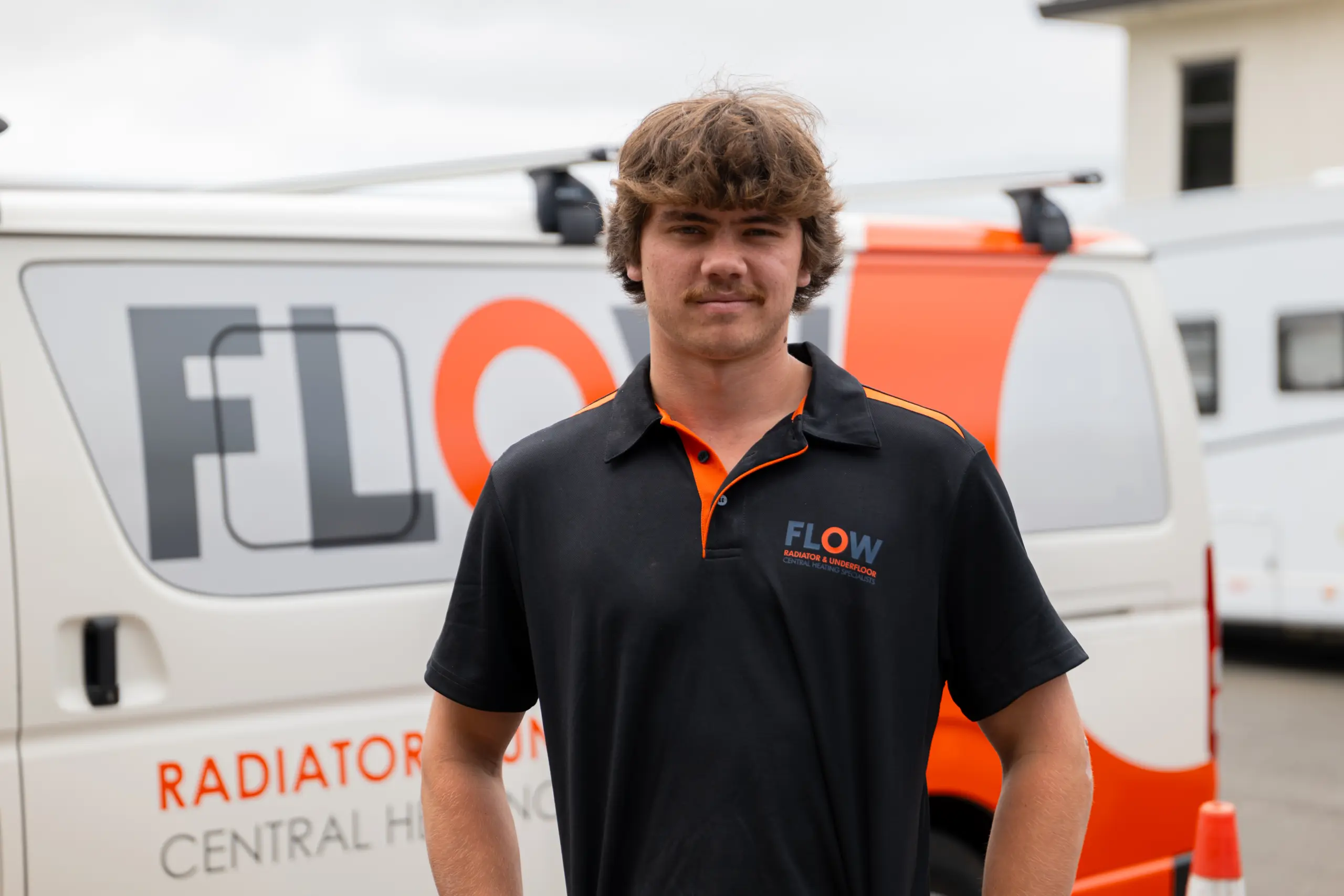 Flow Heating team member beside a branded company van