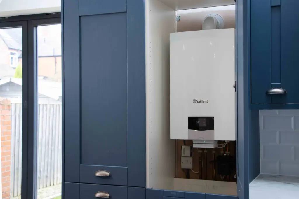Vaillant gas boiler installed inside a navy kitchen cupboard