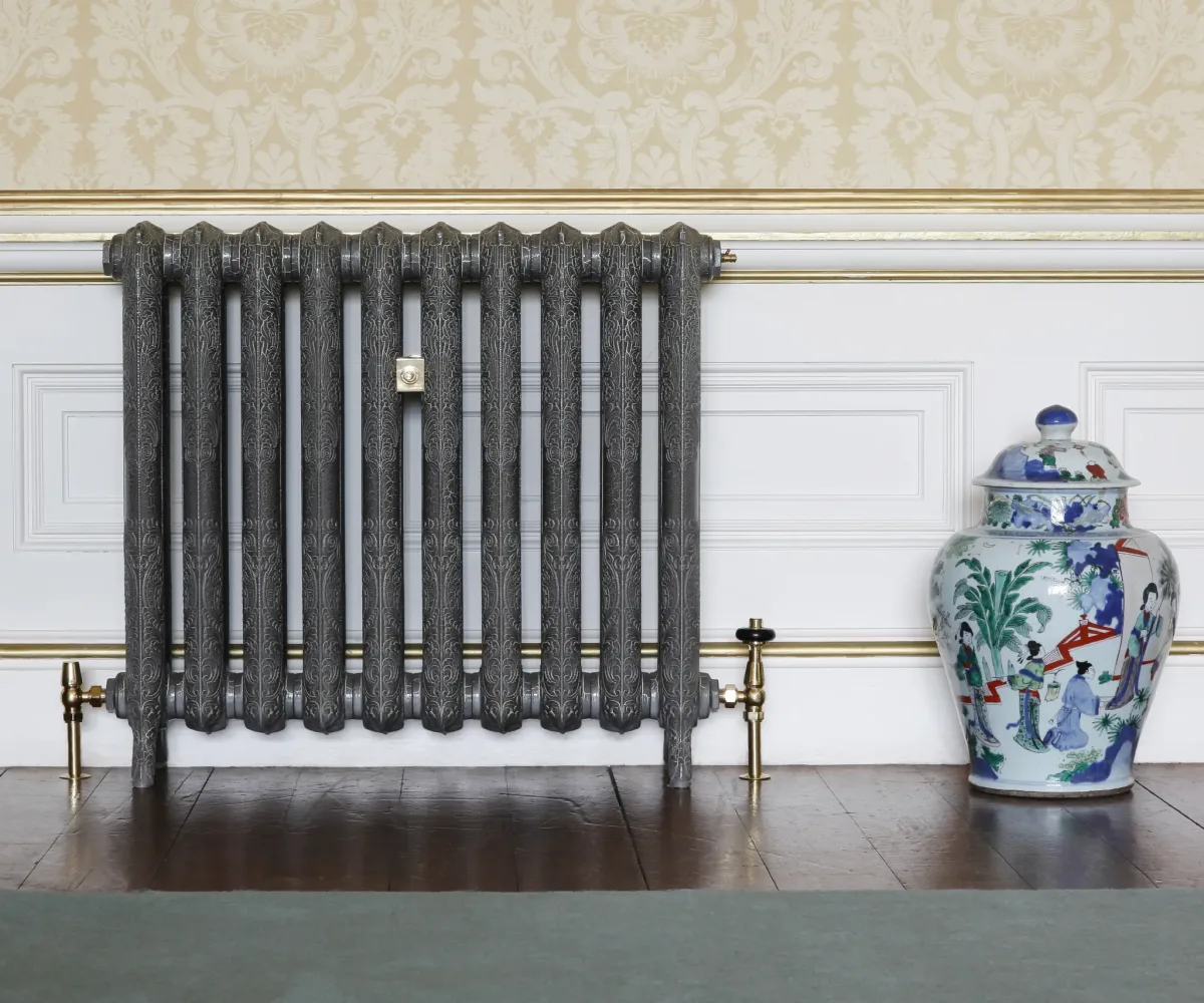 Polished cast iron column radiator against a panelled wall